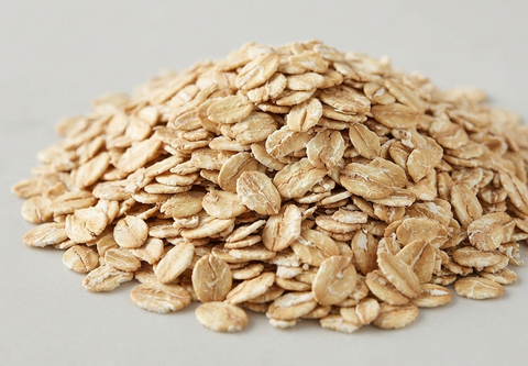 A pile of rolled oats on a light gray background.