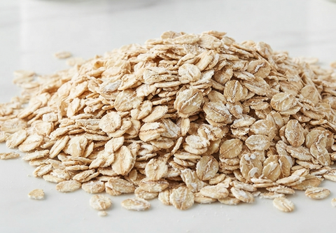 A pile of rolled oats on a light gray surface.